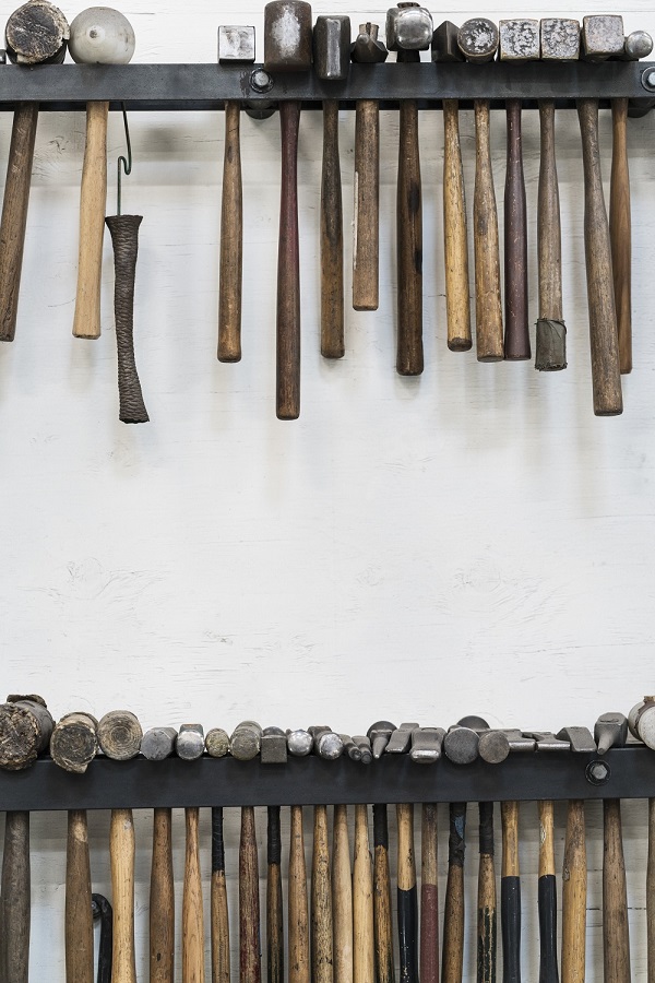 Gros plan d'une sélection de marteaux accrochés à un mur dans un atelier de métallurgie.