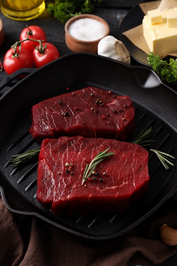 Concept de nourriture savoureuse avec des steaks de bœuf crus sur une table en bois foncé.