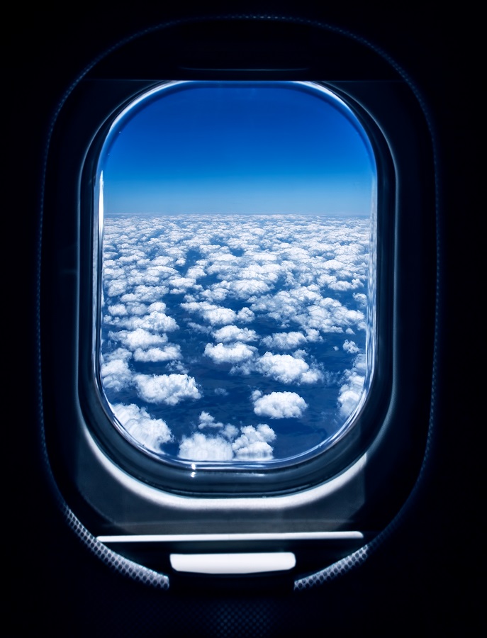 Beaux nuages blancs et cotonneux vus à travers le hublot d'un avion, vue aérienne, concept de voyage en avion.