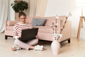 Jeune femme cherchant une assurance emprunteur sur son ordinateur portable dans son salon