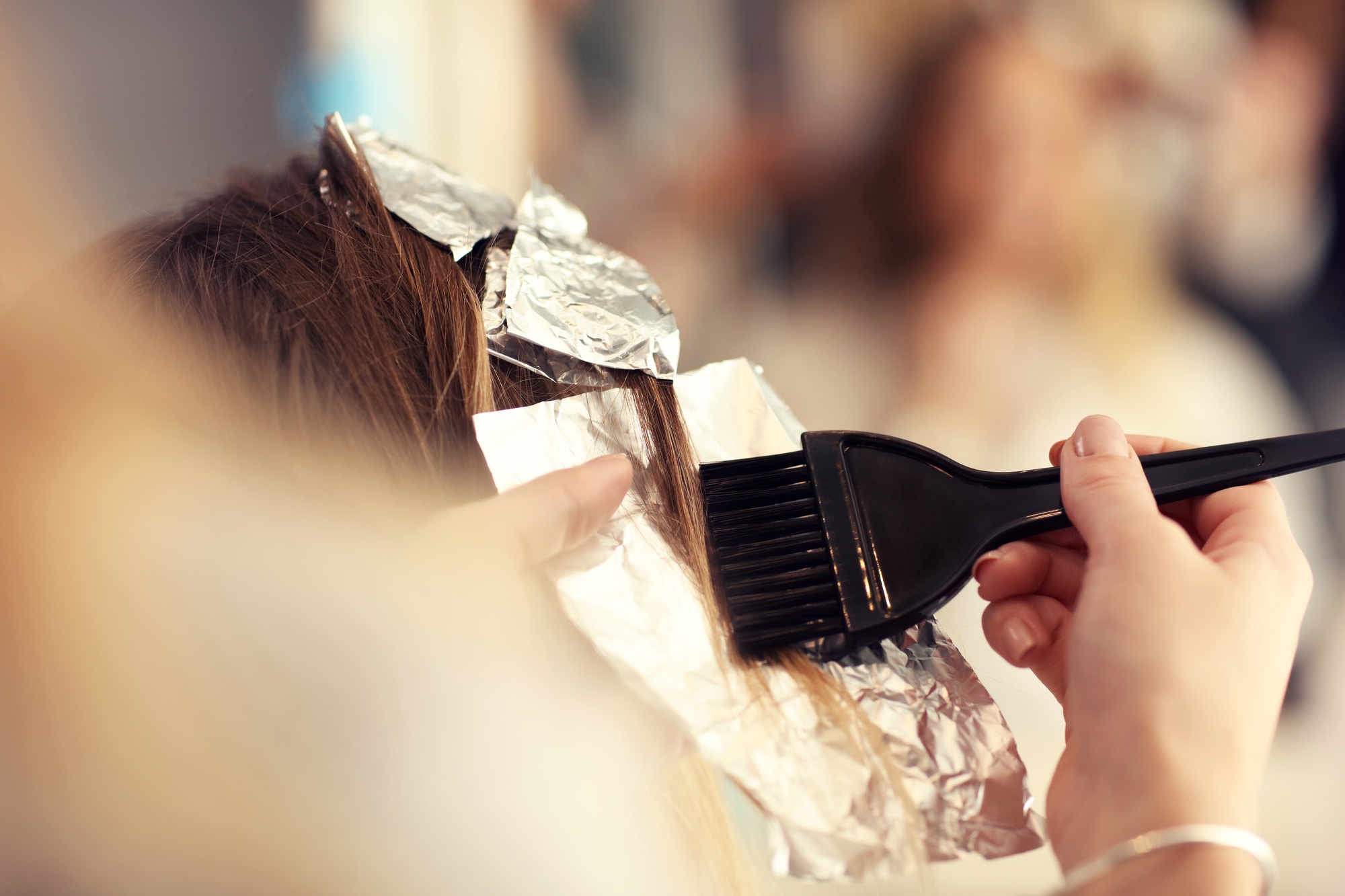 Hairdresser coloring hair in studio