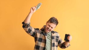Homme qui tient des billets dans sa main et qui danse de joie